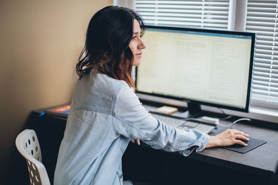 Stock photo: a woman at a desk working on a document on her computer screen